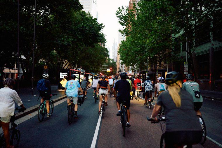 The pack rolling down a city street at dusk, speakers on the racks