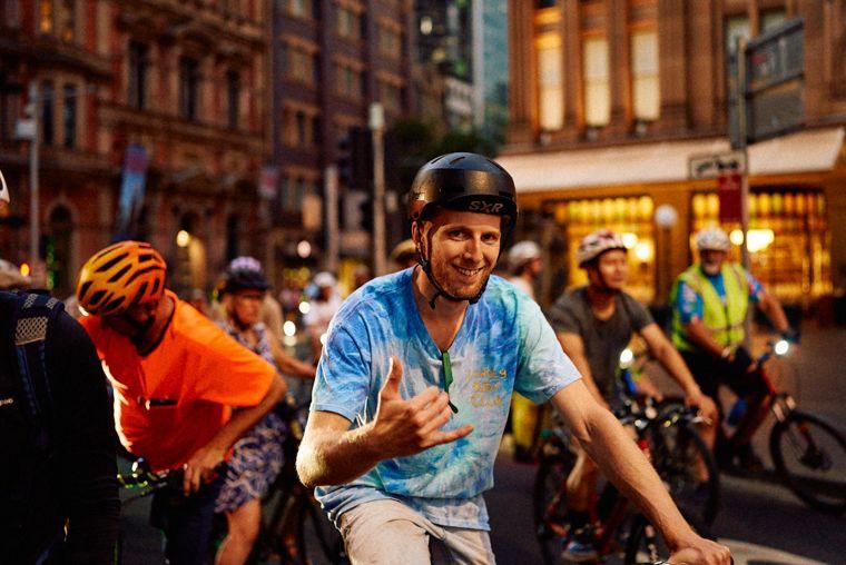 A rider throws a shaka as the pack rolls through the city at night